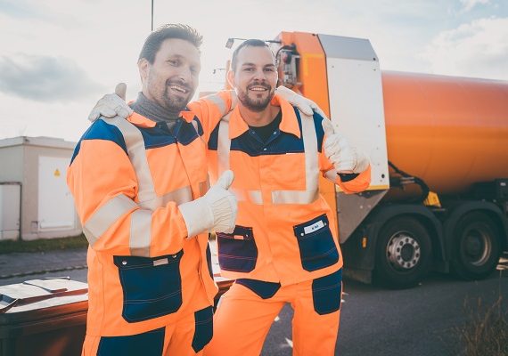 Garbage removal workers giving a thumbs-up in front of disposal truck
